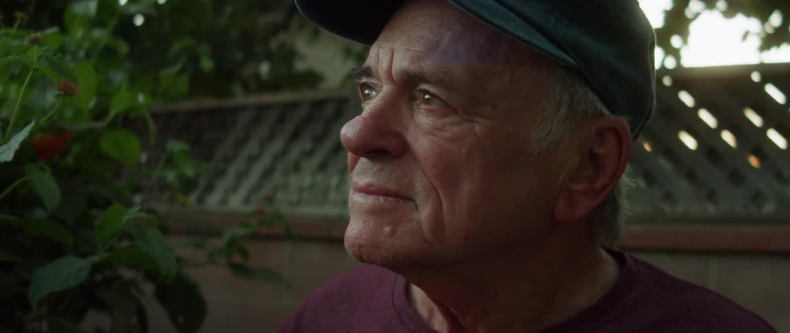 Portrait of an elderly person in the garden with a cap and a happy emotional facial expression