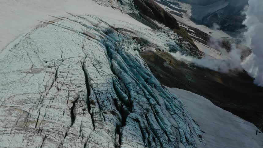 Aerial of volcanic mountain with ice and smoke during the day