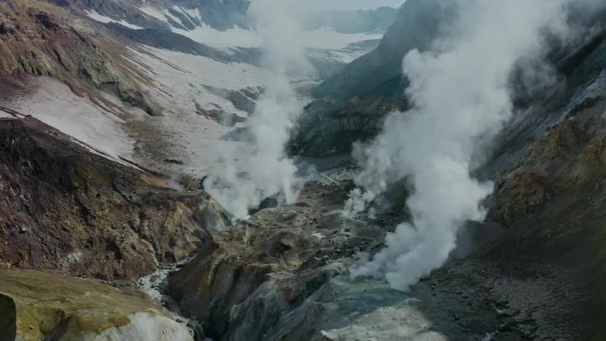 Steam is rising from the geyser between the mountains