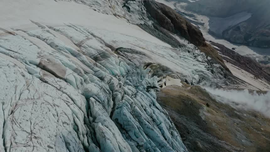 Aerial view of frozen mountains with smoke rising from the ground