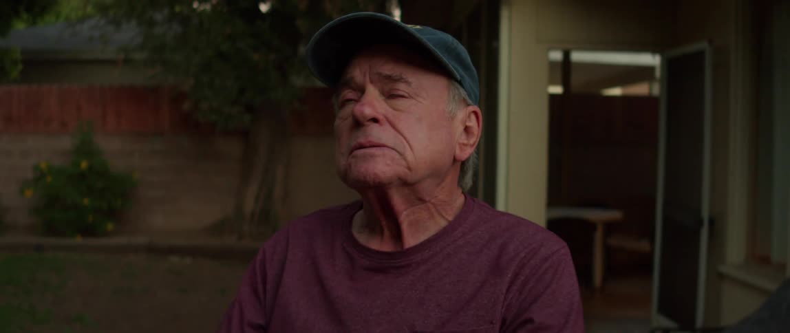A sad man putting a cap on his head standing in the garden