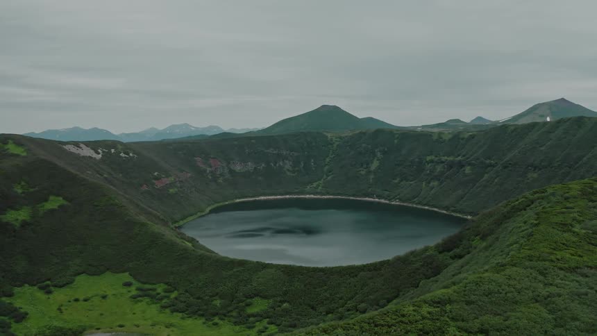 Aerial panorama of a lake amidst a mountain range with a cloudy sky