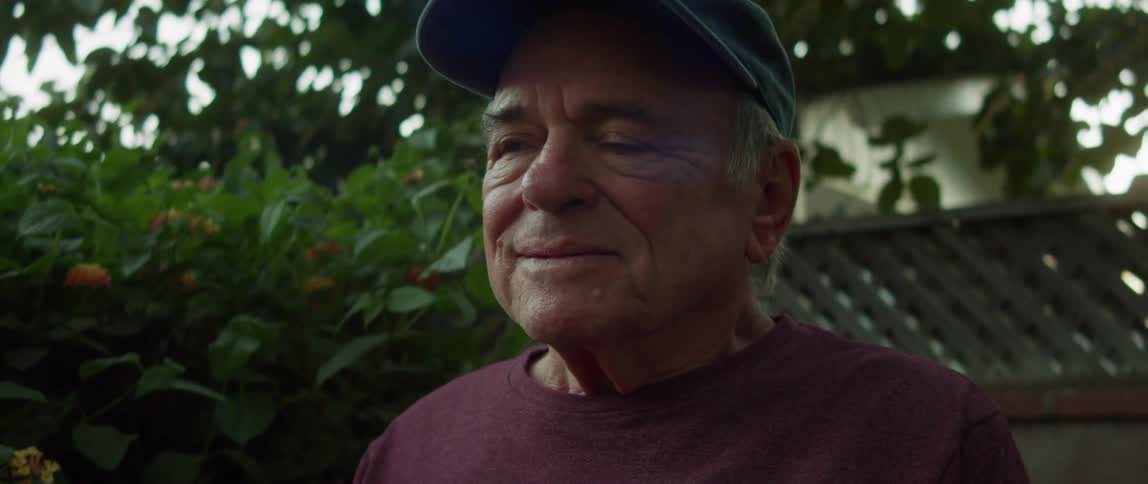 A man smiles by his garden