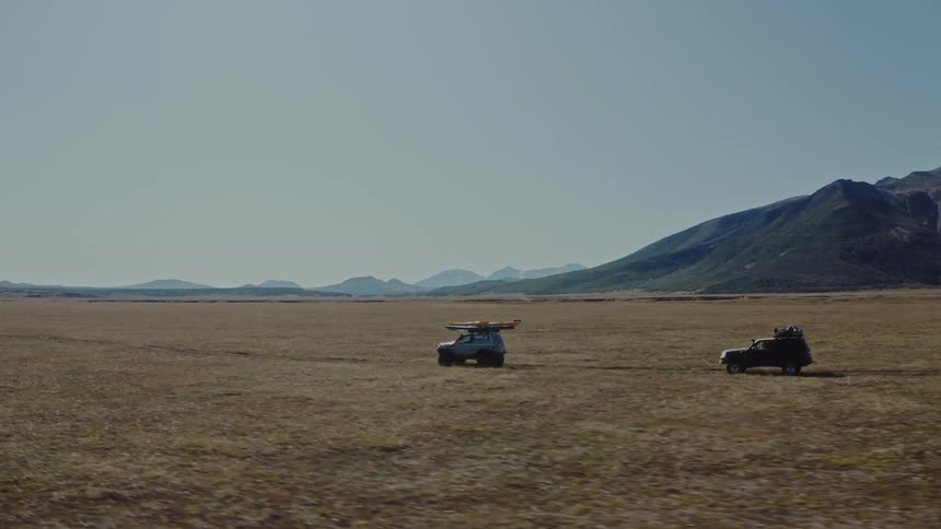 Cars driving on a dirt road in the countryside during the day