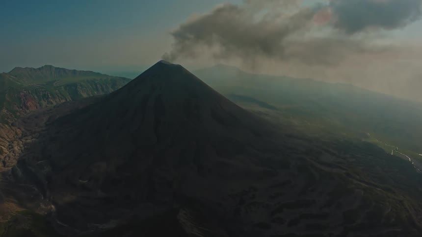 Aerial panorama of a volcano emitting smoke
