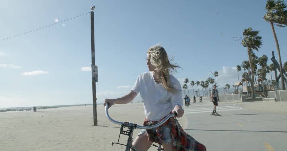 A woman rides her bike as she looks out over the beach