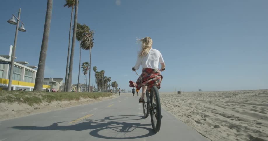 A woman rides her bike near a beach