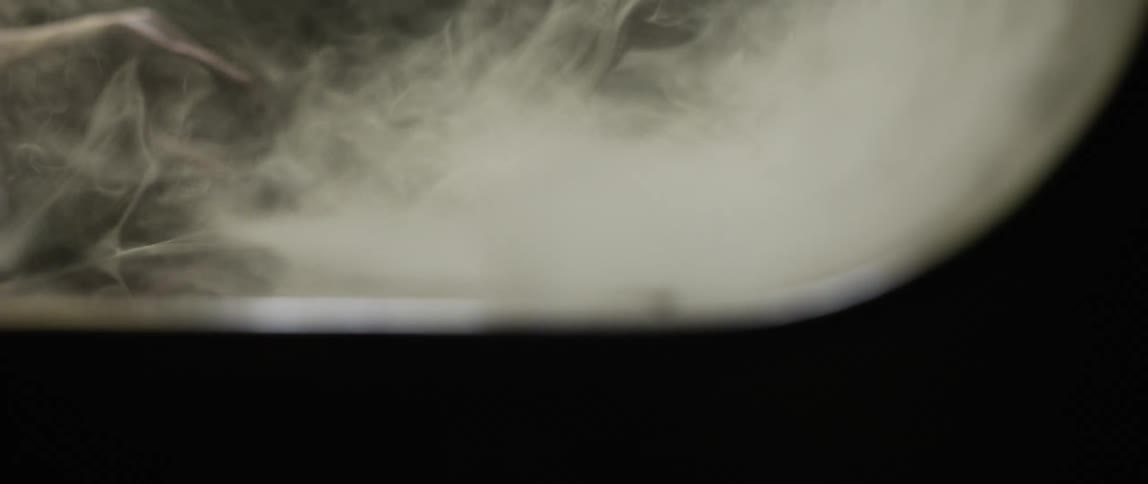 Person passes hand through vapor while stroking smooth surface