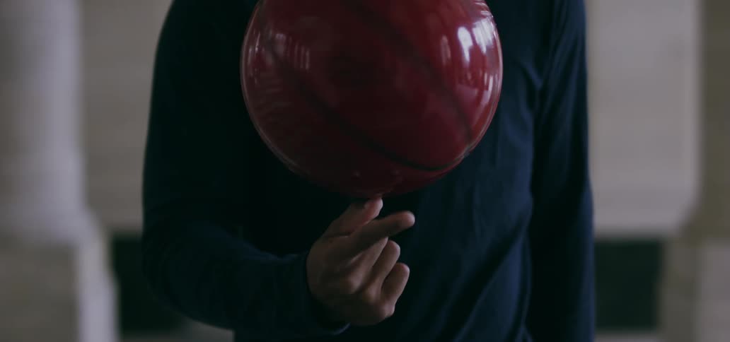 Person holding a red ball with the tips of their fingers spinning it