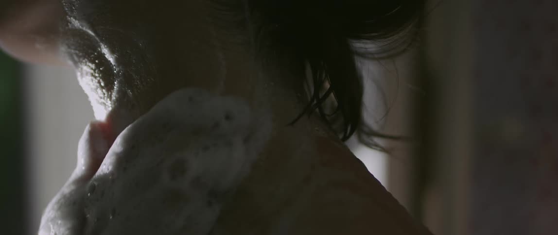 Closeup of a womans neck being massaged with cleansing foam by hands