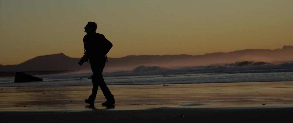 Silhouette of a man walking on the beach sand in the morning