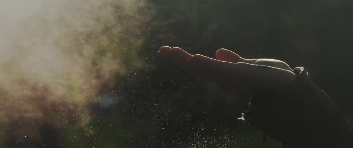 Dust blown from persons palm sparkles in the light
