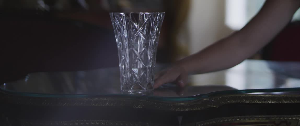 A person pushing a glass goblet from the table