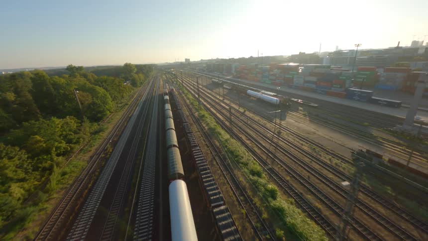 Aerial view of a train track next to a port with containers in the morning