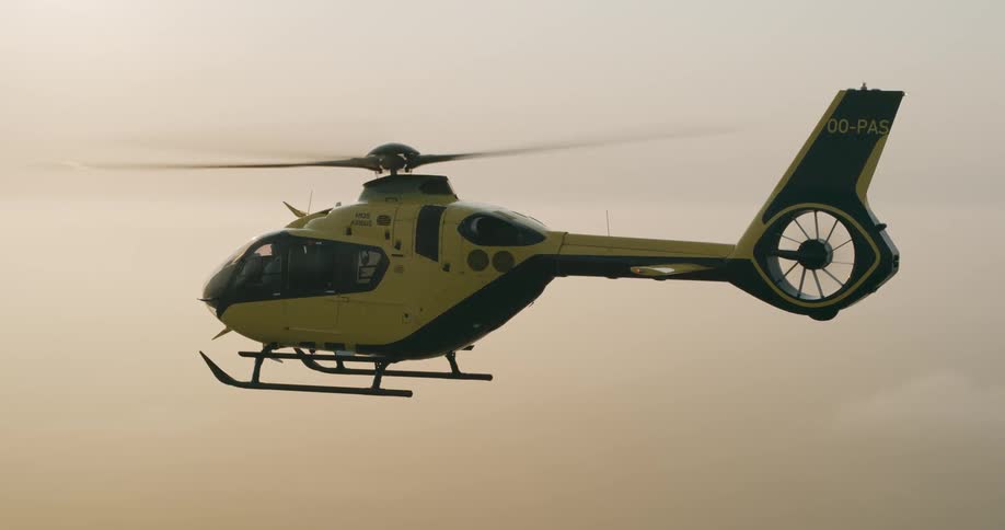 Helicopter flies through red tinted fog over a rural landscape