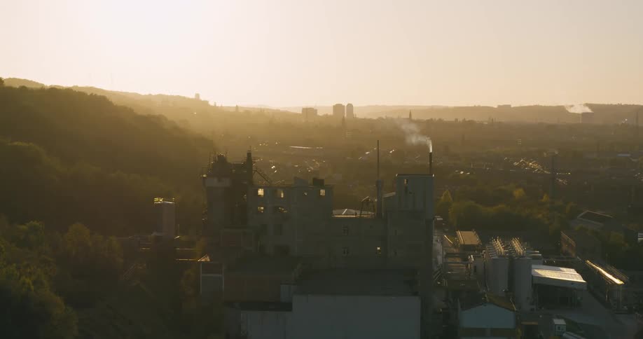 Aerial view of a factory next to a mountain on a morning with sunlight reflections