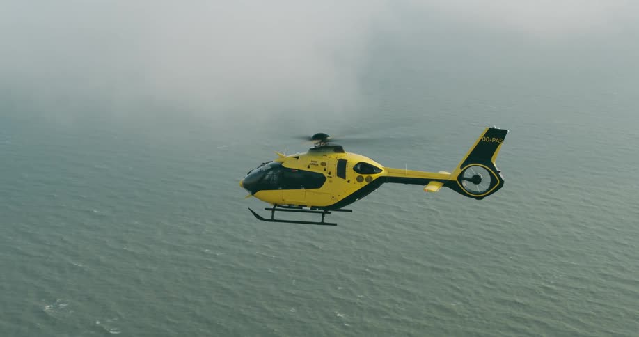 Helicopter flying over the sea and passing through clouds