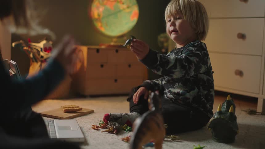 Two children playing on the floor with dinosaur toys