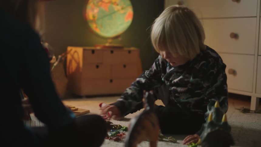 Two brothers sitting on the bedroom floor playing with toys