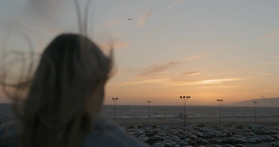 A woman watches the sunrise over a parking lot