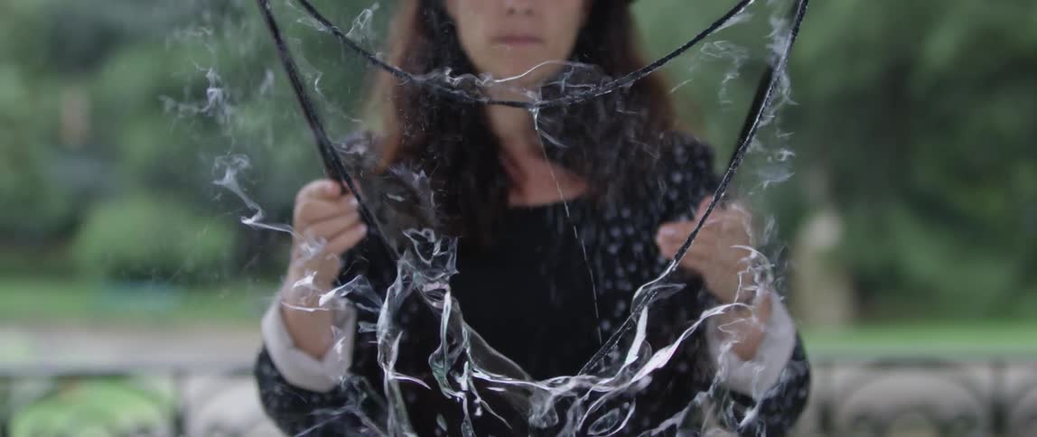 Woman holding a platform with a huge soap bubble bursting in slow motion