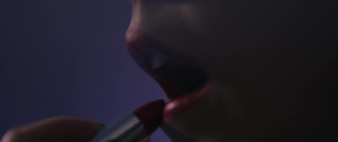 Closeup of a womans lips applying red lipstick