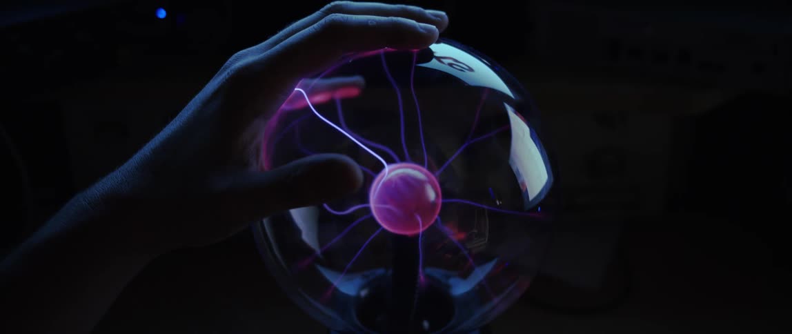 Closeup of a globe with purple electric waves and hands of a person placed around the globe