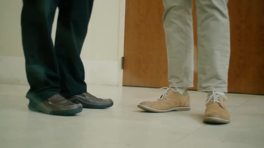 Legs of two people standing side by side indoor
