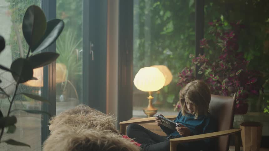 A child playing video games sitting on a chair in the living room