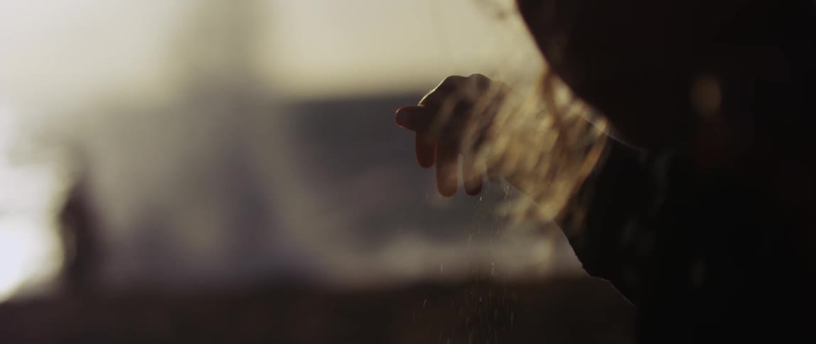 A person drops sand on the beach