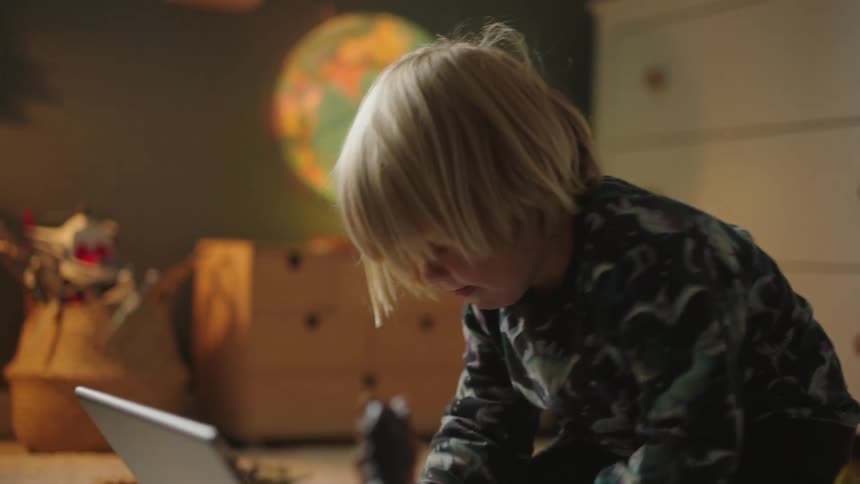A child typing on the computer on the bedroom floor