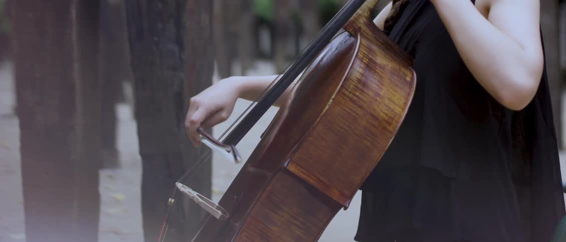 A female playing a string instrument outdoor during the day