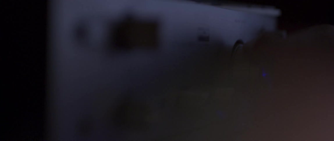 A hand turning the control of an old sound system in a dark room