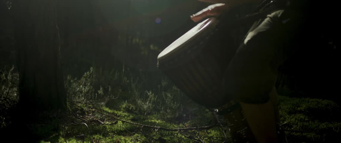 Hands of a person playing drums in an outdoor environment with greenery