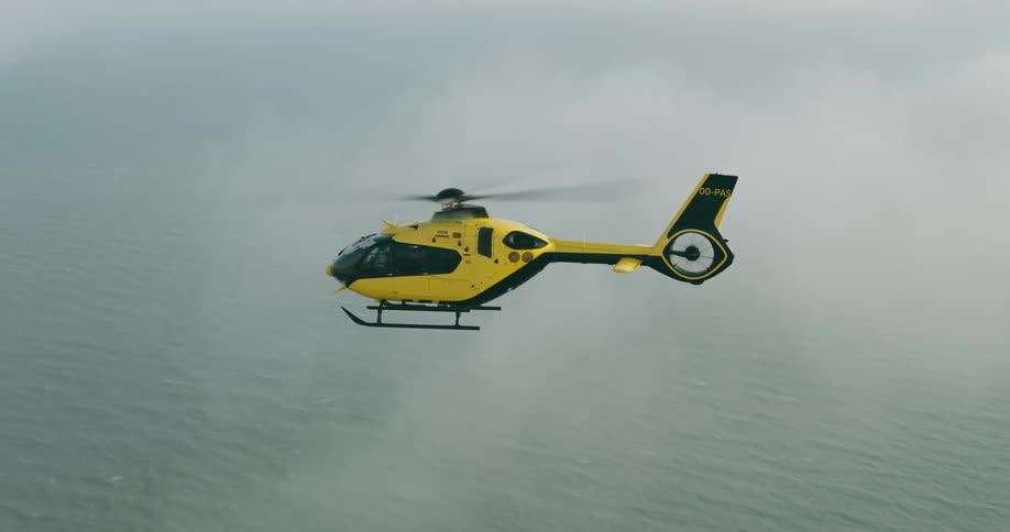 The helicopter is flying over the water