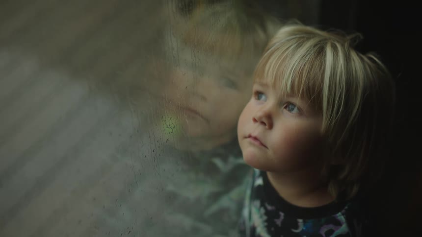 Portrait of the face of a young boy gazing out of the window