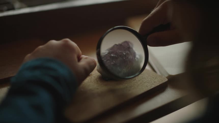 A child is looking at a crystal under a magnifying glass