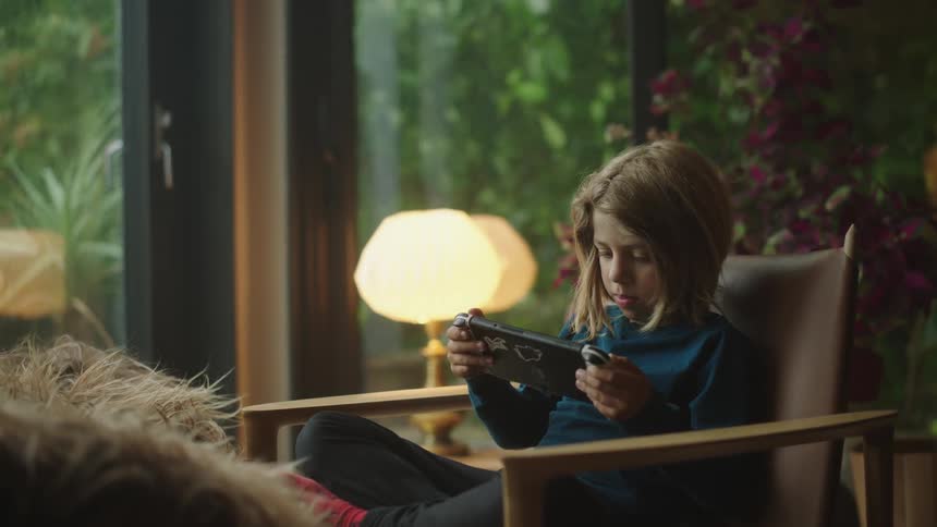 A boy sitting in a chair focused on a video game