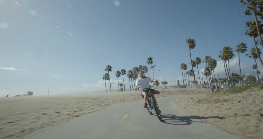 A woman is riding her bicycle on a path near the beach