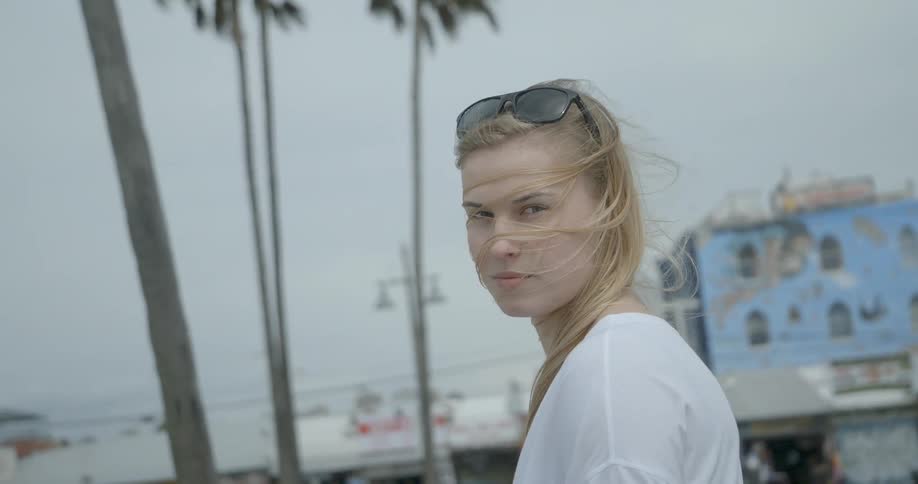 A woman is standing outside on a cloudy windy day