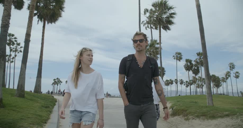 A man and woman walk along a sidewalk on a windy day