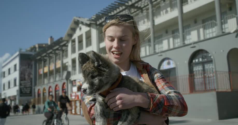 A woman is holding a small dog