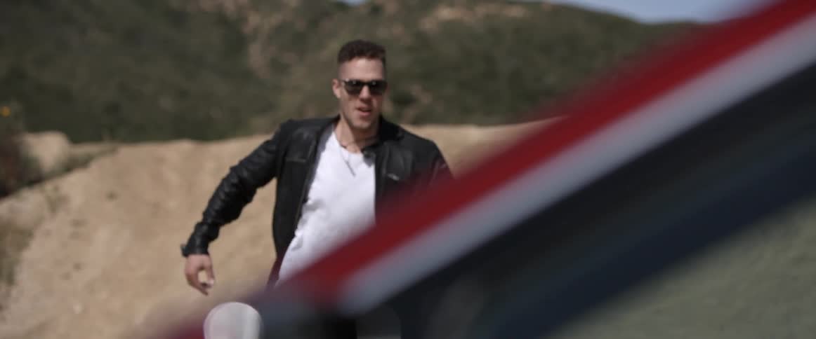 A man runs down a small dirt hill towards a car door