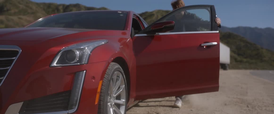 A person runs and climbs into a car