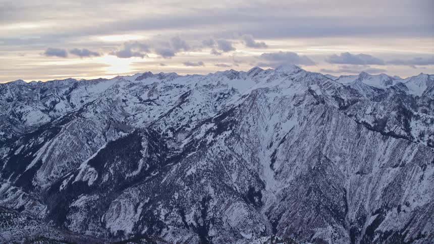 Aerial panorama over the mountains and peaks covered in snow under a morning sky