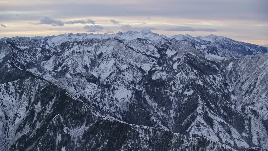 Aerial panorama over the mountains and peaks covered in snow under a morning sky