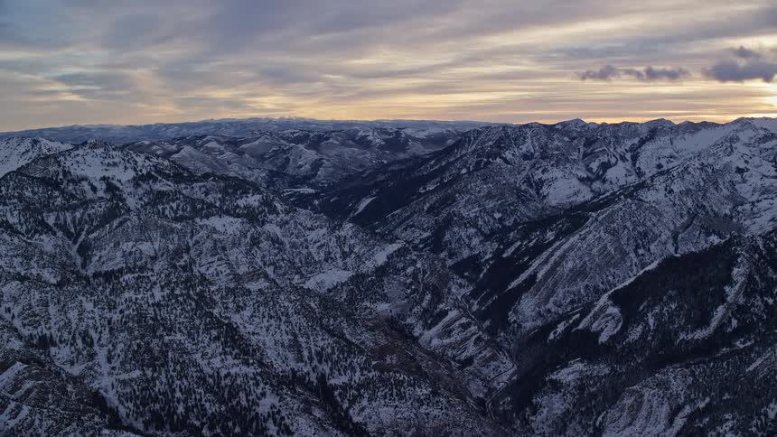 Aerial view of the snowy slopes of a mountain range at morning
