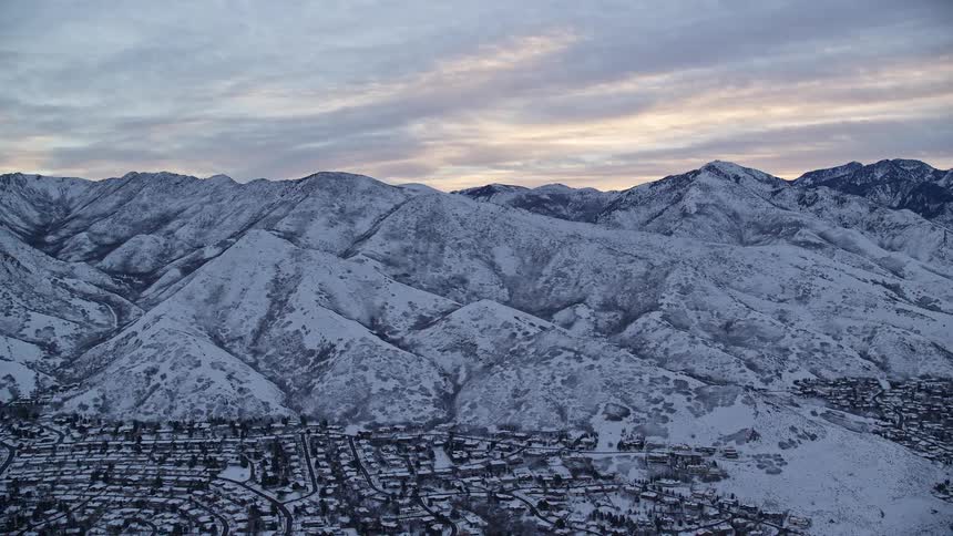 Aerial panorama of a village next to snowcovered mountains under a morning sky