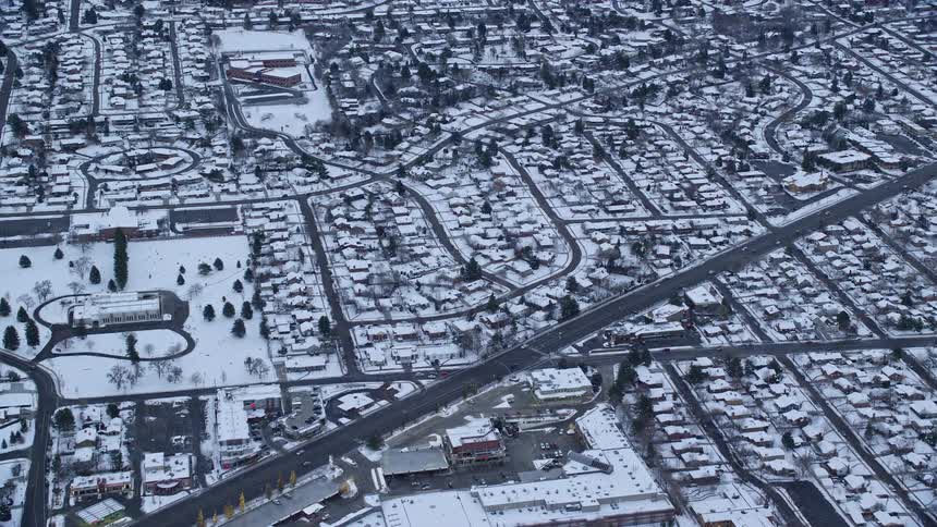 Aerial of snow covered residential neighborhood crossed by busy roads