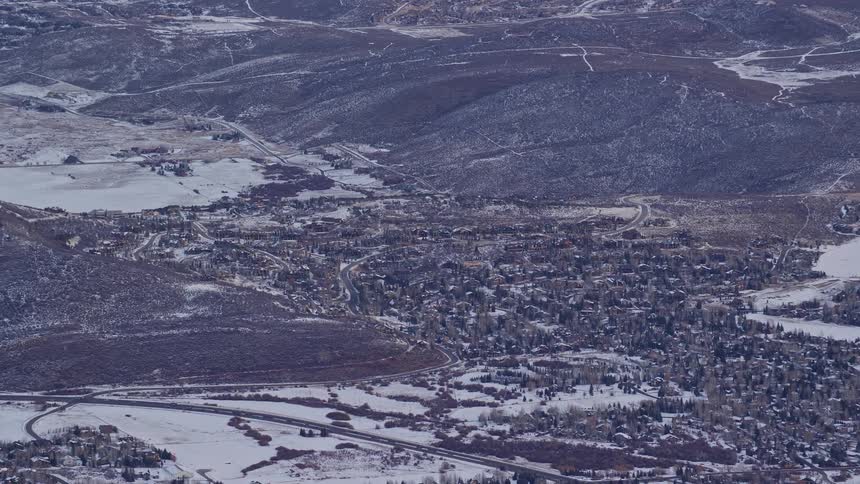 Aerial panorama of a mountain range and terrain with an urban city covered in snow